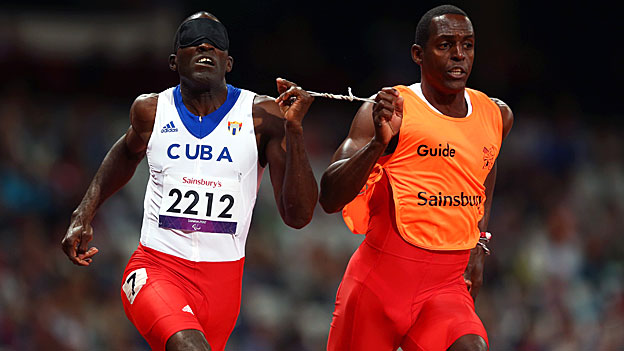 Yaseen Perez Gomez guides Arian Iznaga of Cuba around the track in the men